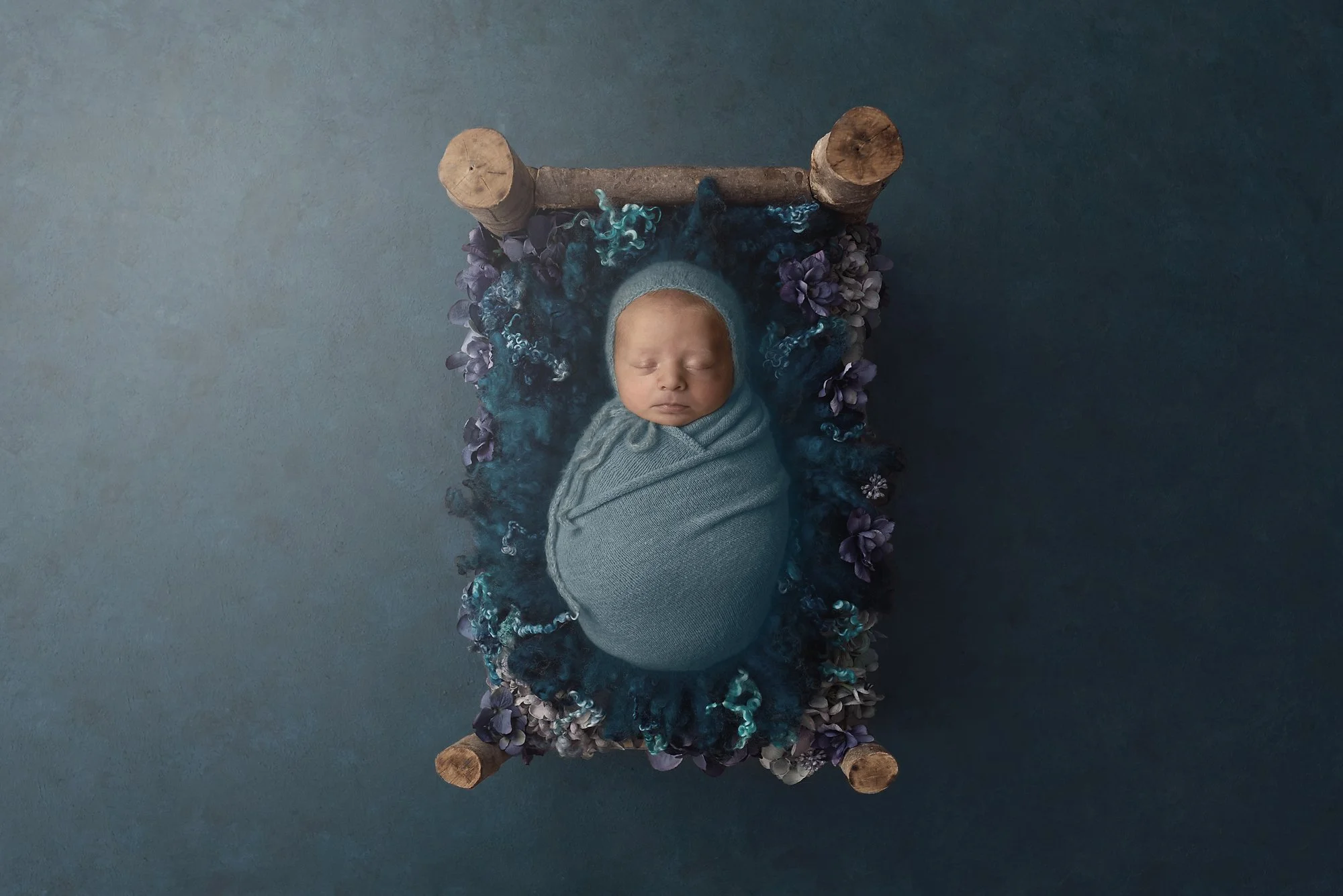 baby wrapped in blue asleep on bed, newborn photographer, hills district
