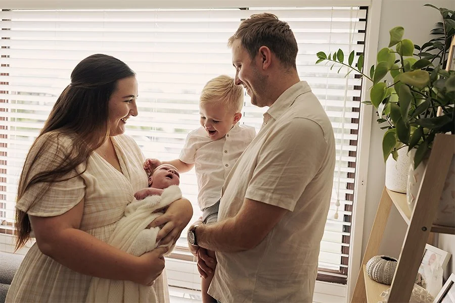 Newborn baby photographed with older sibling during newborn photoshoot