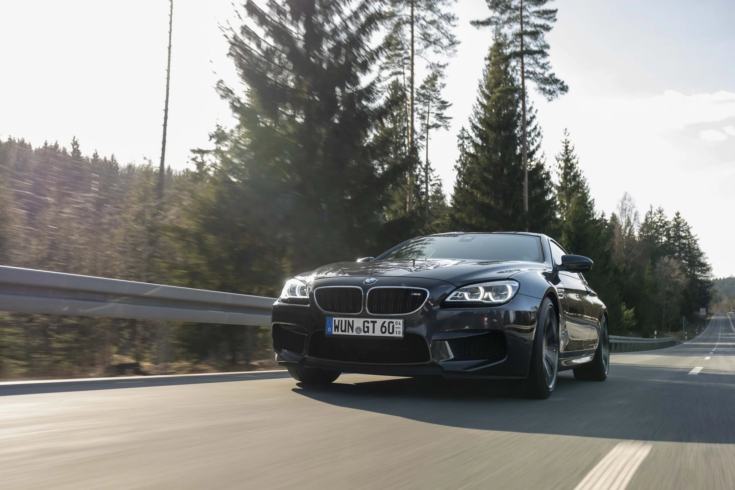 Ein schwarzes Auto, das auf einer Straße durch eine waldige Landschaft fährt.