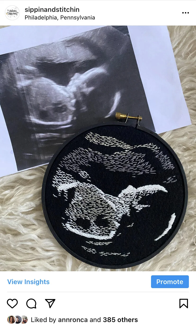 Ultrasound image of a developing fetus, placed next to a black embroidery hoop featuring a white stitched depiction of a dinosaur on a furry surface.
