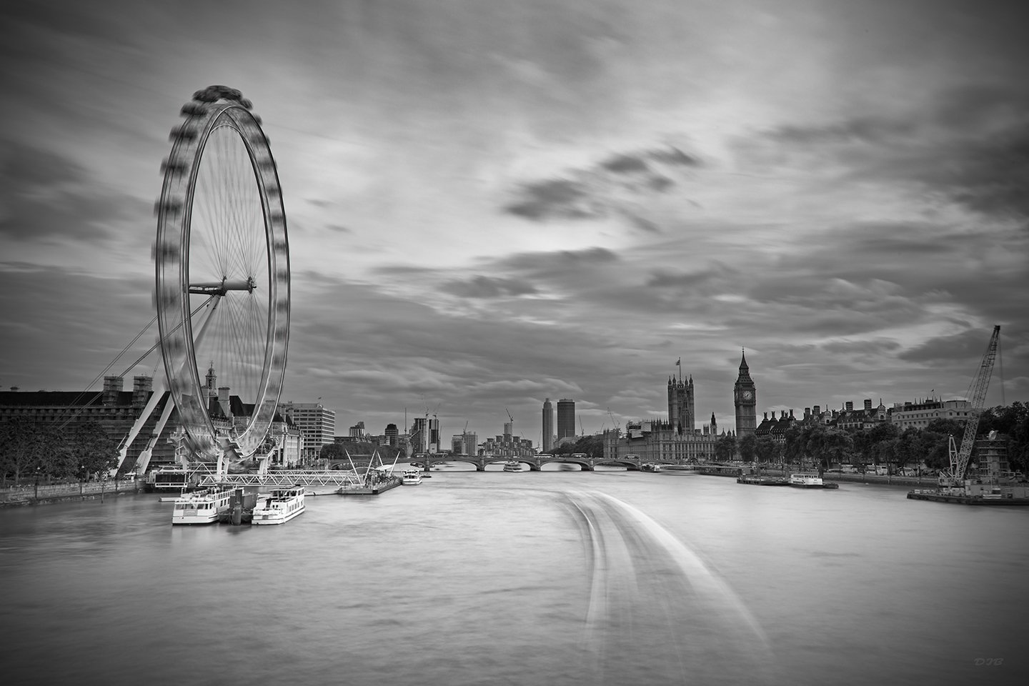 Black and white photo of the London skyline with the London Eye on the left, the River Thames in the foreground, and Big Ben and other historic buildings in the background.