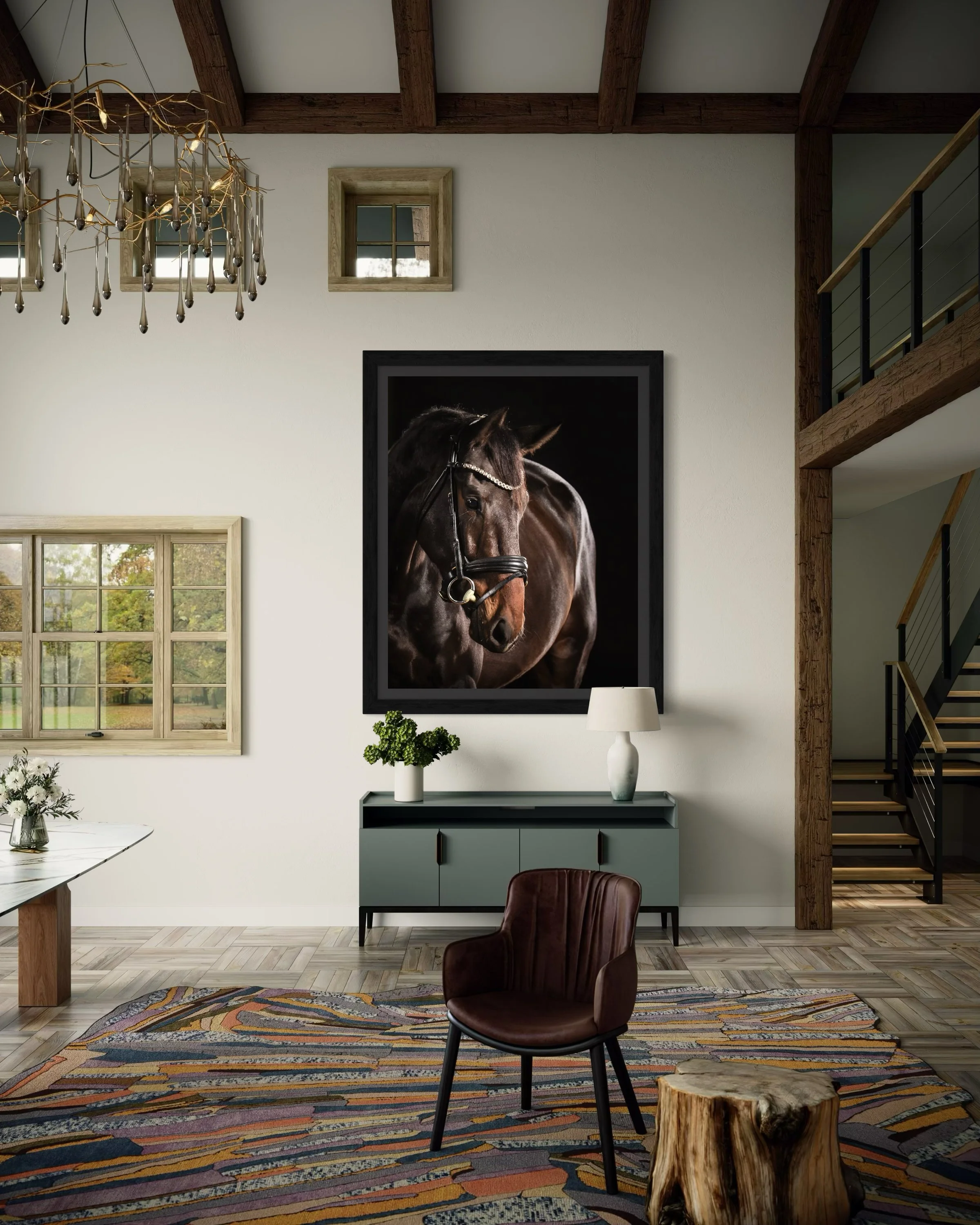 A contemporary living room with a large framed horse portrait on the wall, a light blue sideboard with a white lamp and a green plant, a leather chair, a patterned rug, a wooden table, a window showing outdoor greenery, a staircase with wooden and black railing, and a modern chandelier.
