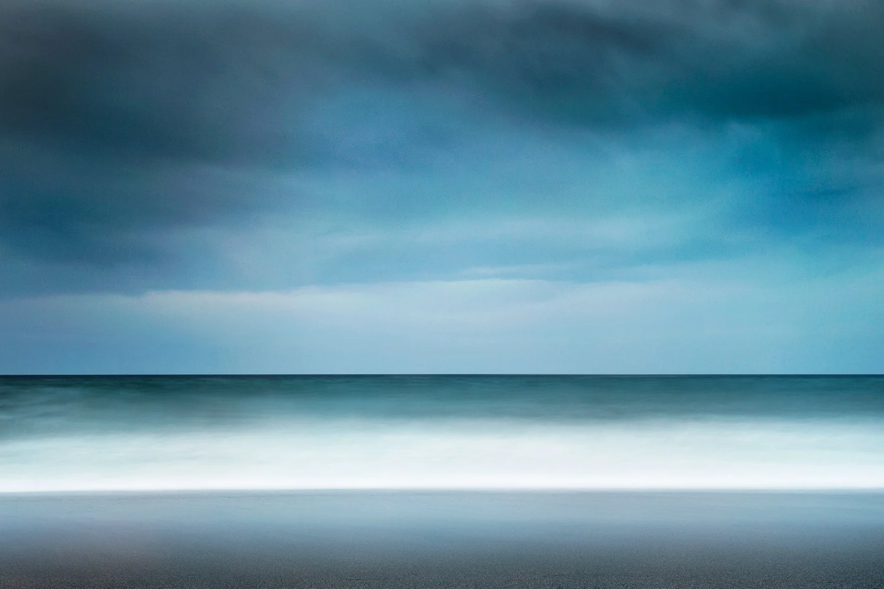 Empty beach with dark cloudy sky over the ocean