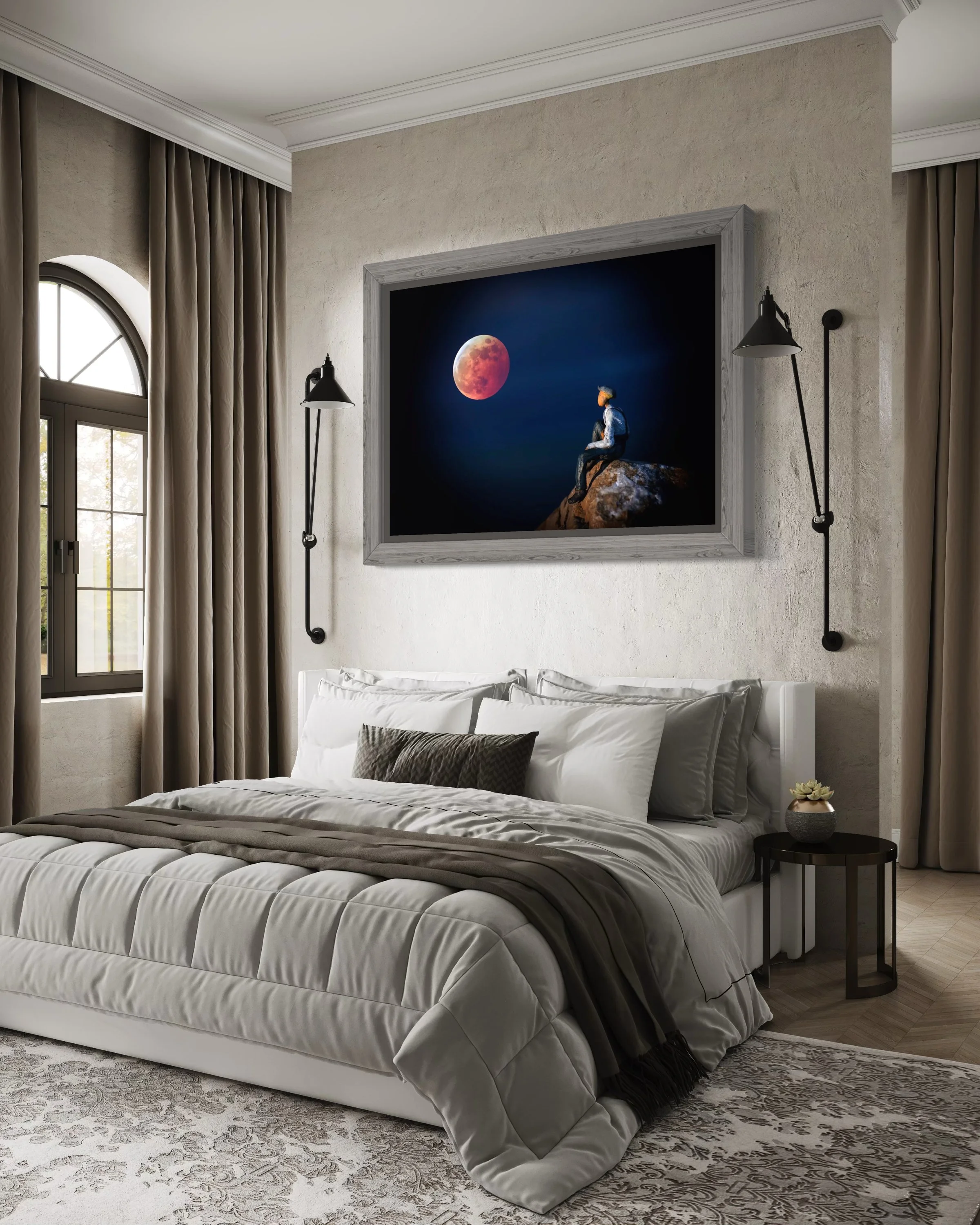 A bedroom with a bed covered in white and gray bedding, a small black side table with a potted plant, beige curtains, a window, and a large framed photo of a person sitting on a rock looking at the moon on the wall above the bed.