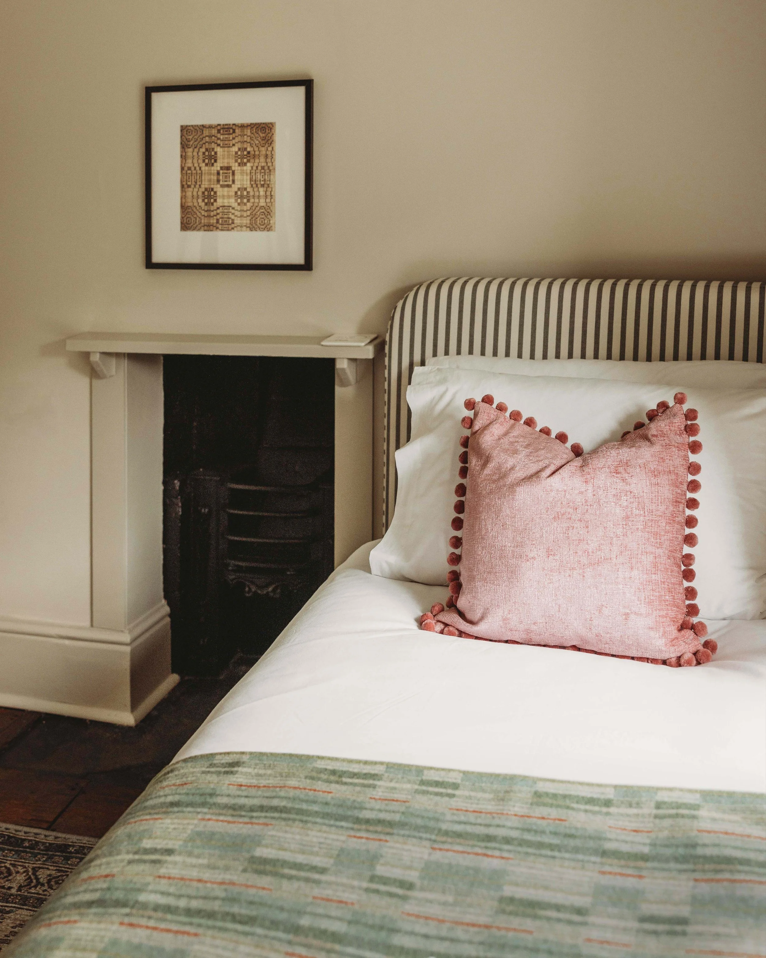 Cottage bedroom, pink cushion, teal green welsh blanket, art