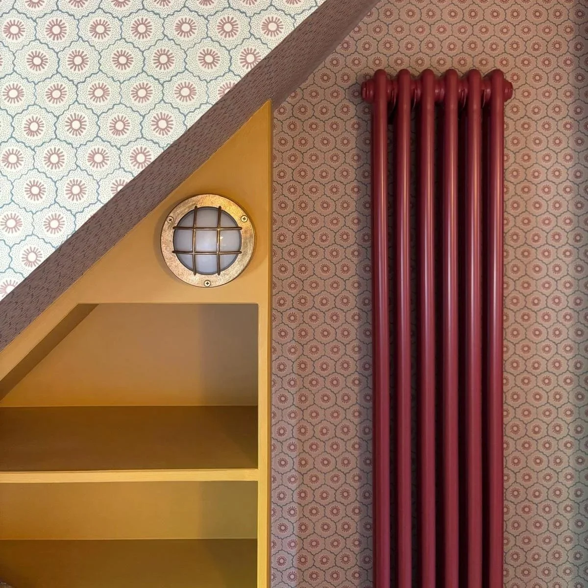 yellow shelves built under eaves with red radiator and small-print wallpaper