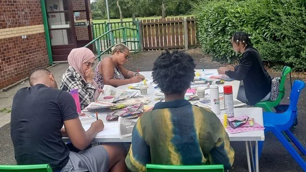 A group session at the Fika Welie organisation, using donated pens on the table