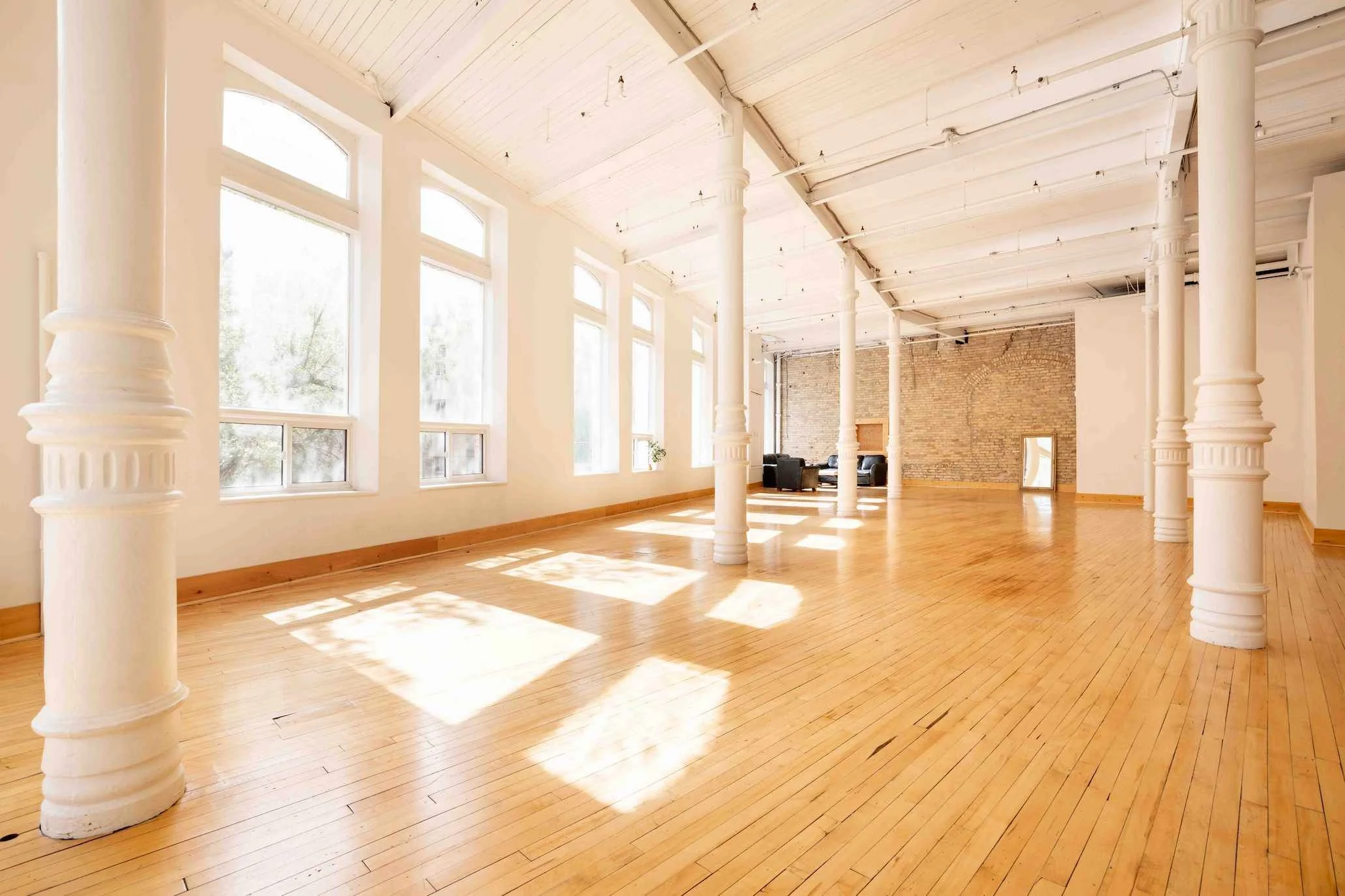 Main shooting floor at 204 Photography's Winnipeg headshot studio, with arched windows, white columns and original hardwood in the Exchange District.