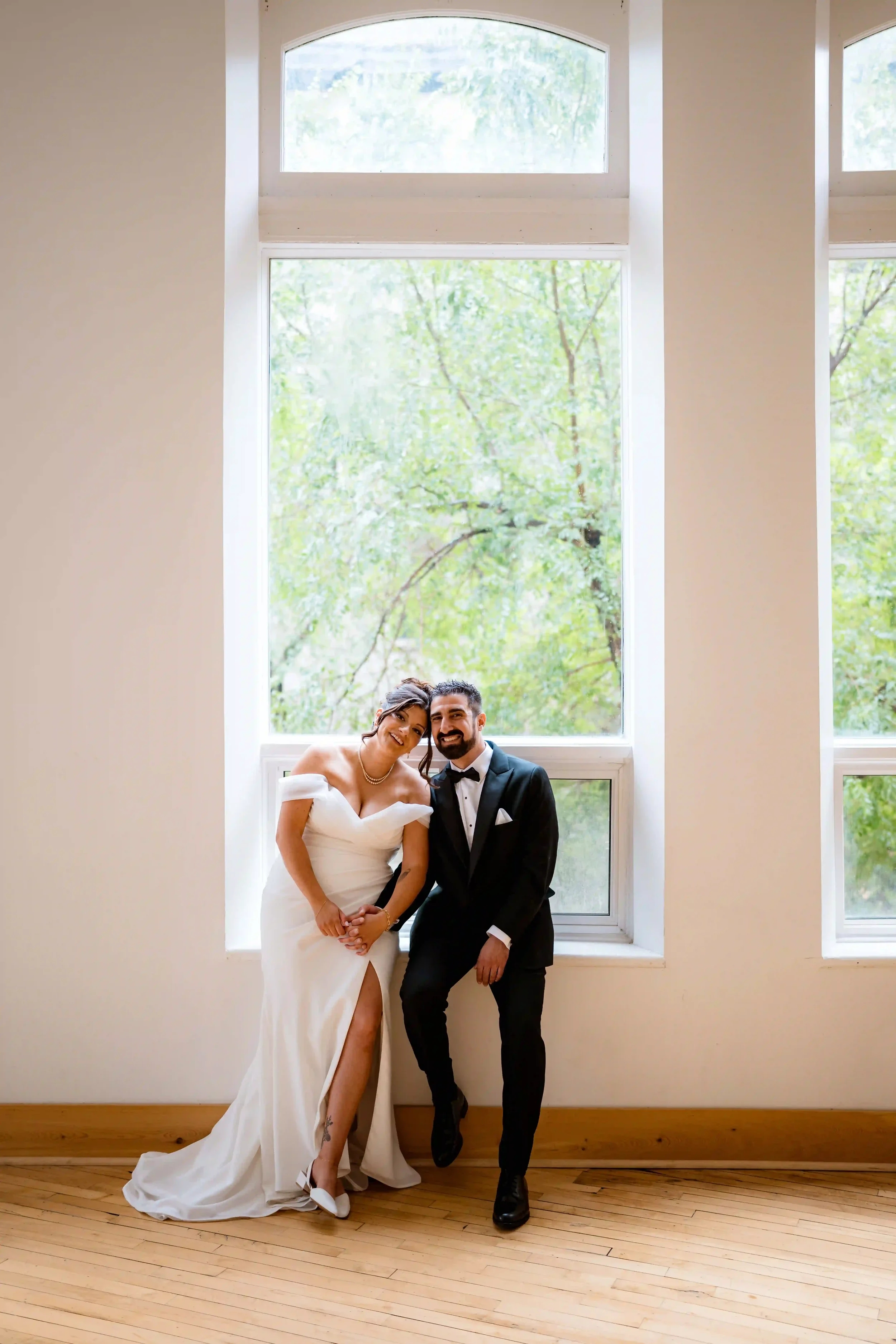 Bride and groom sharing a quiet moment by large windows at Winnipeg’s wedding ceremony venue, Two Zero Four.