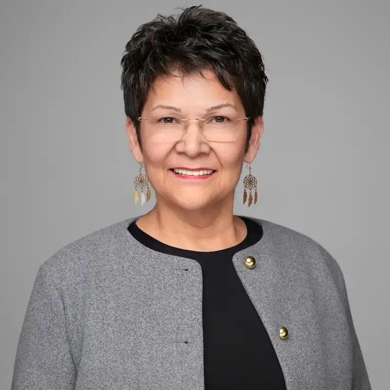 Executive headshot of a woman in a grey cardigan and glasses against a light grey backdrop – professional portrait by 204 Photography Winnipeg