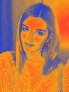 A young woman with shoulder-length hair winks at the camera, wearing a light-colored turtleneck sweater and hoop earrings, in a black and white photo.