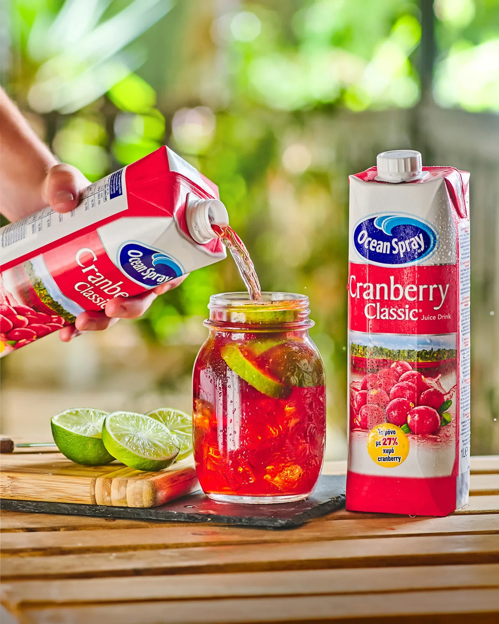 Commercial beverage photography by Vasilis Geravelis με εφέ ροής (pouring shot) για τον χυμό Ocean Spray Cranberry Classic. Δημιουργική φωτογράφιση cocktail σε γυάλινο βάζο με λάιμ και πάγο σε ξύλινο τραπέζι.