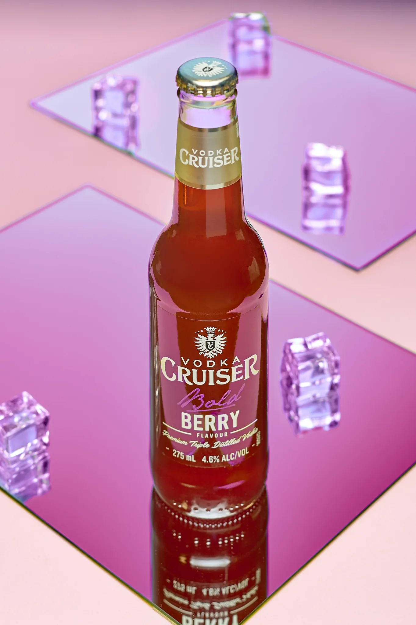 Commercial beverage photography by Vasilis Geravelis με concept καθρεφτών και αντανακλάσεων για το μπουκάλι Vodka Cruiser Bold Berry. Δημιουργική studio φωτογράφιση προϊόντος με παγάκια σε παστέλ ροζ και μοβ φόντο.
