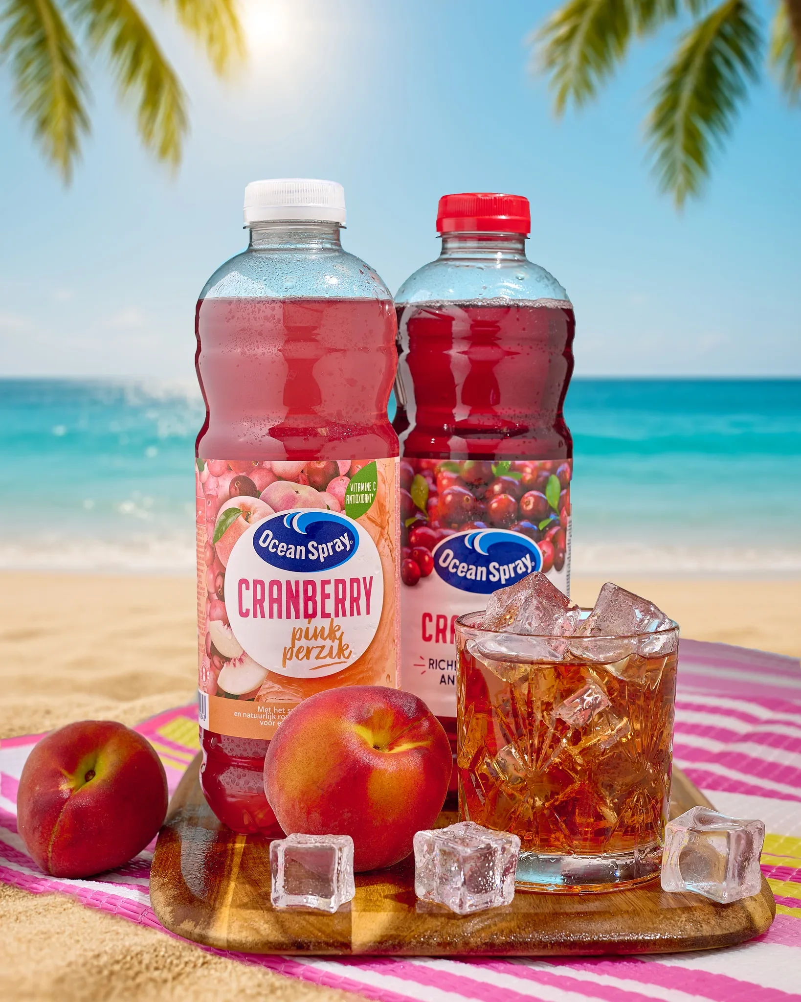 Commercial beverage photography by Vasilis Geravelis για τον χυμό Ocean Spray Cranberry Pink Perzik. Καλοκαιρινή διαφημιστική φωτογράφιση προϊόντος με φόντο παραλία, φρέσκα ροδάκινα και ποτήρι με πάγο.