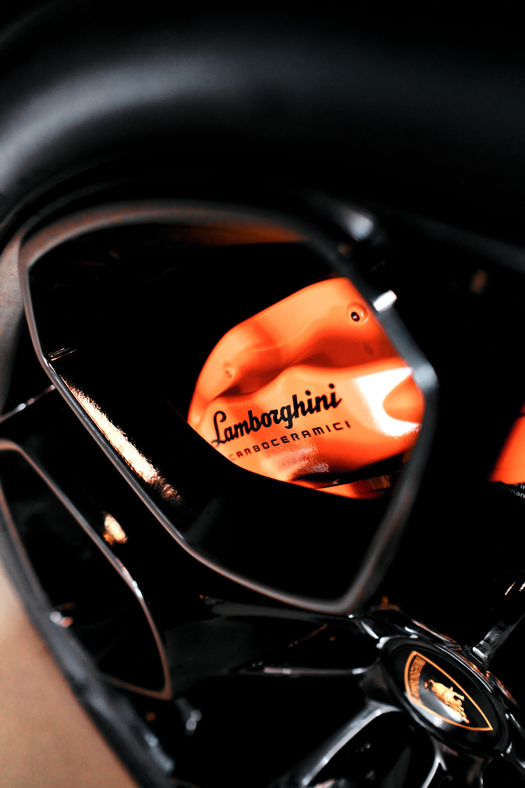 Close-up of a black Lamborghini with an illuminated orange logo and a focus on the vehicle's detail.