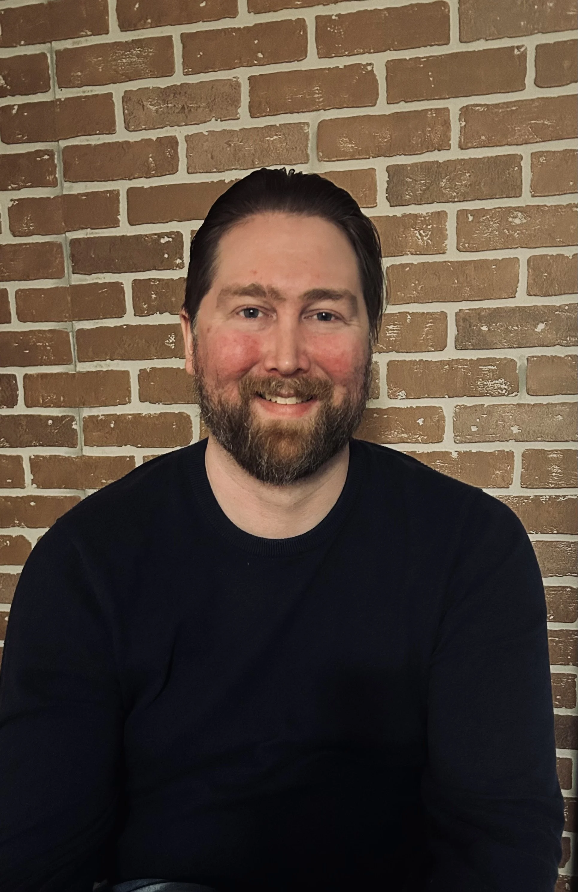 a headshot of Nick Jones in front of a brick wall