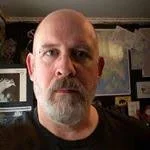 Head shot of Scott Fitzgerald . Bald headed man with graying beard