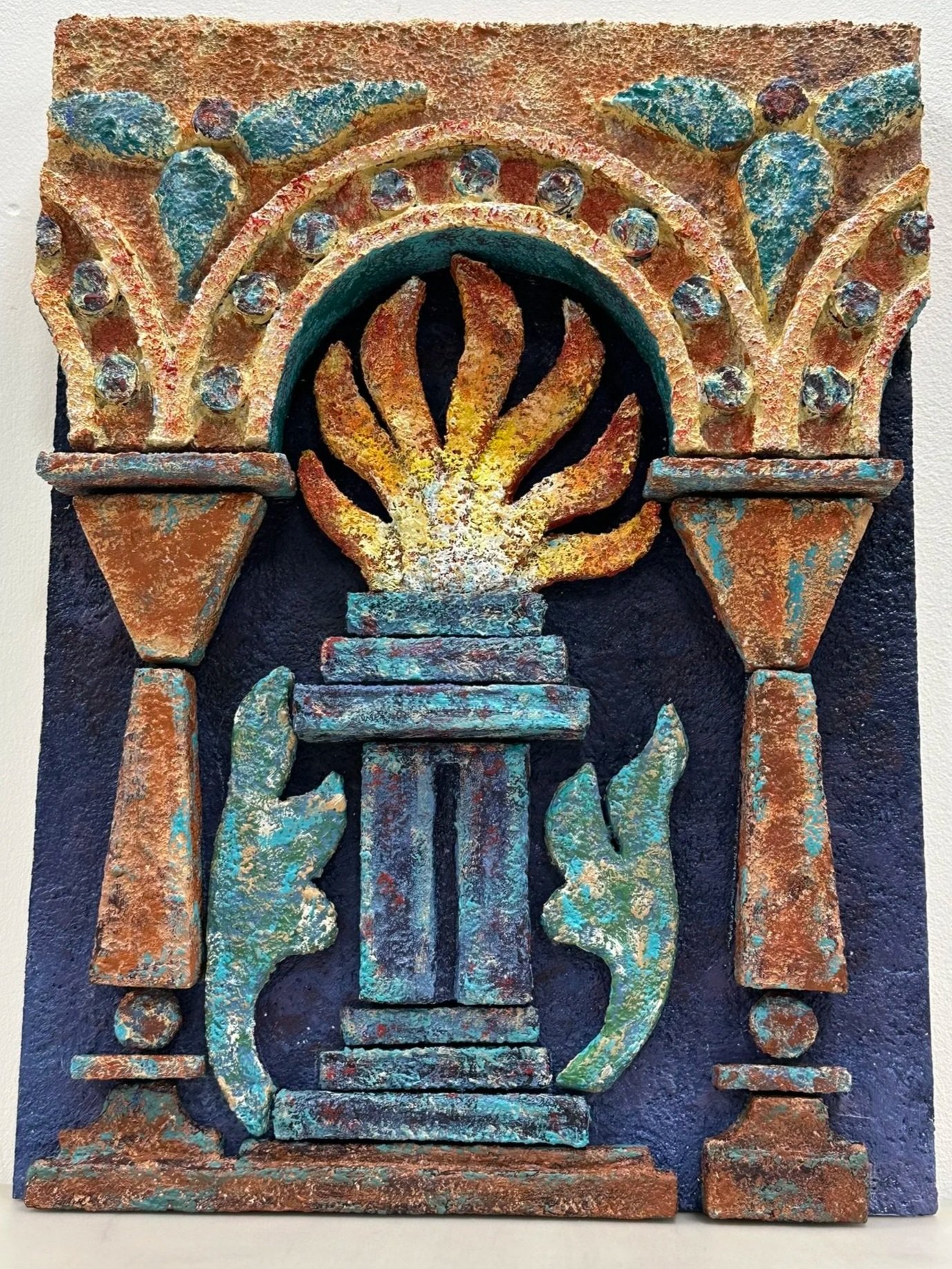 High-relief mixed-media wall sculpture featuring a central fire framed by architectural arches and geometric motifs. Inspired by Zoroastrian heritage and ancient ossuary imagerey, the work combines textured surfaces and sculptural depth.