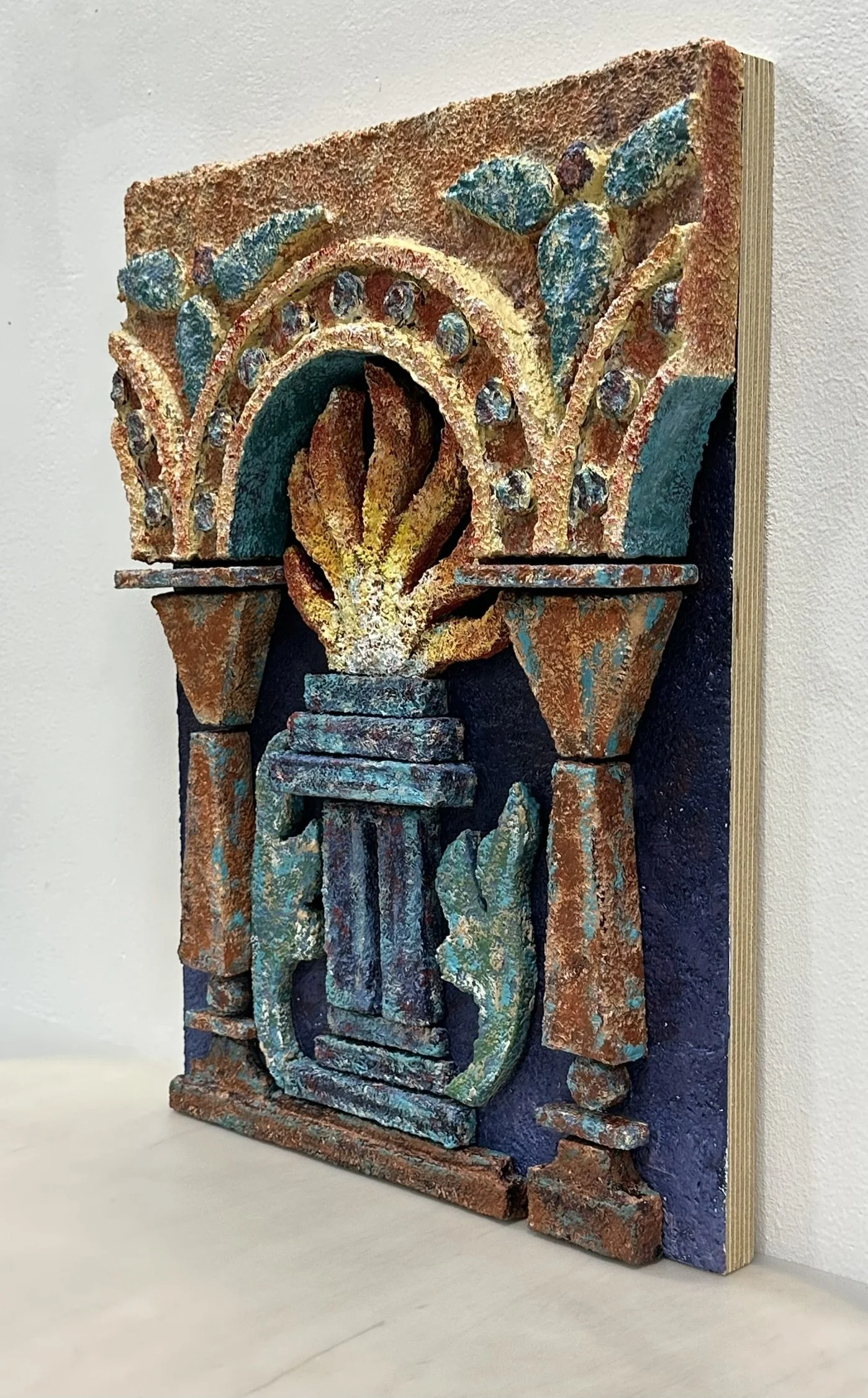 High-relief mixed-media wall sculpture featuring a central fire framed by architectural arches and geometric motifs. Inspired by Zoroastrian heritage and ancient ossuary imagerey, the work combines textured surfaces and sculptural depth.