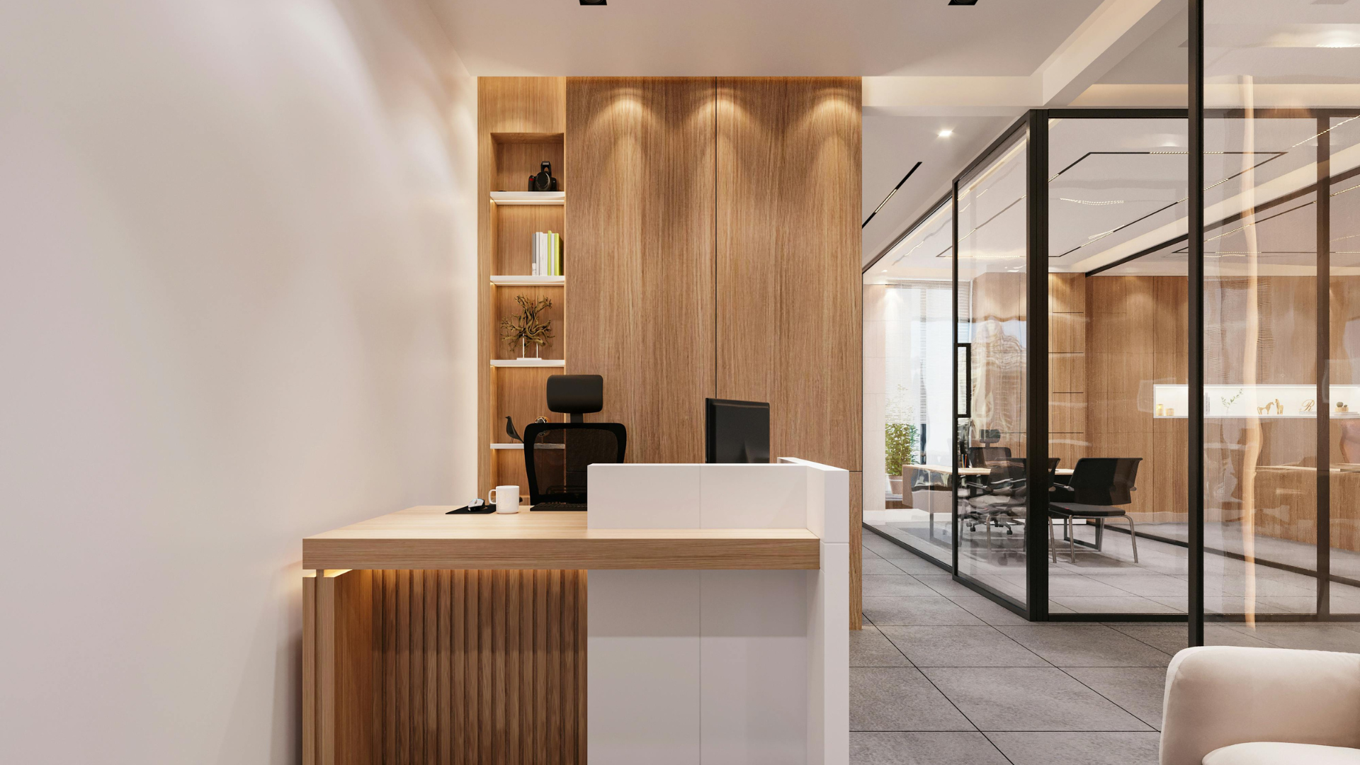 Modern office reception area with a wooden desk, black office chair, and a white coffee mug. Behind the desk are wooden wall panels and a glass conference room with chairs and a large window.