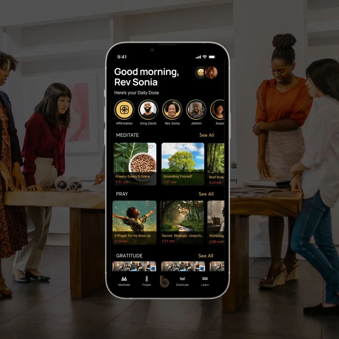 Smartphone screen displaying a wellness app interface with greetings, meditation, prayer, and gratitude sections, in a room with five women around a wooden table.