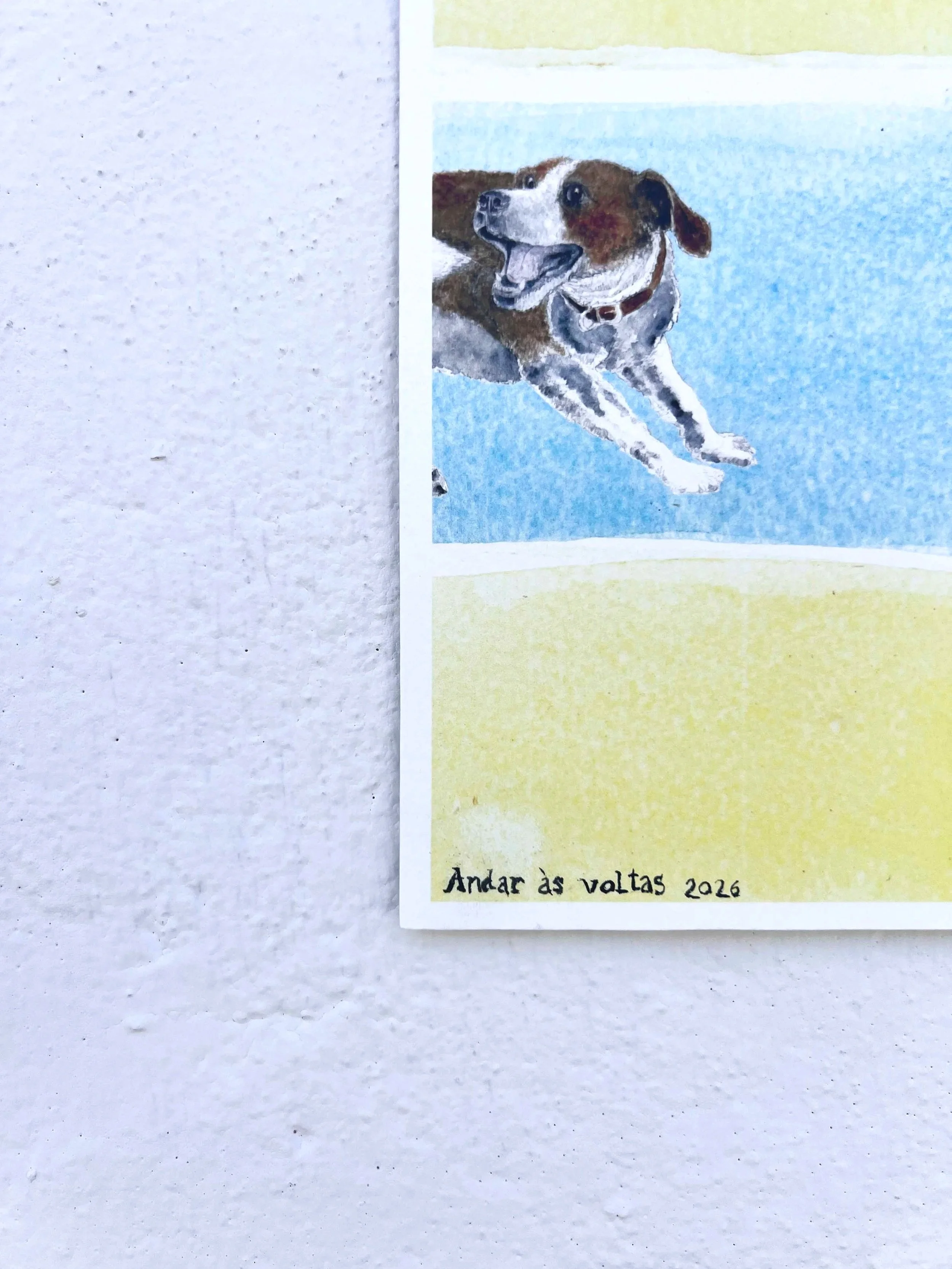 Drawing of a happy dog with brown and white fur, lying on blue ground with a yellow background. Handwritten text at the bottom reads, "Andar às voltas 2026."