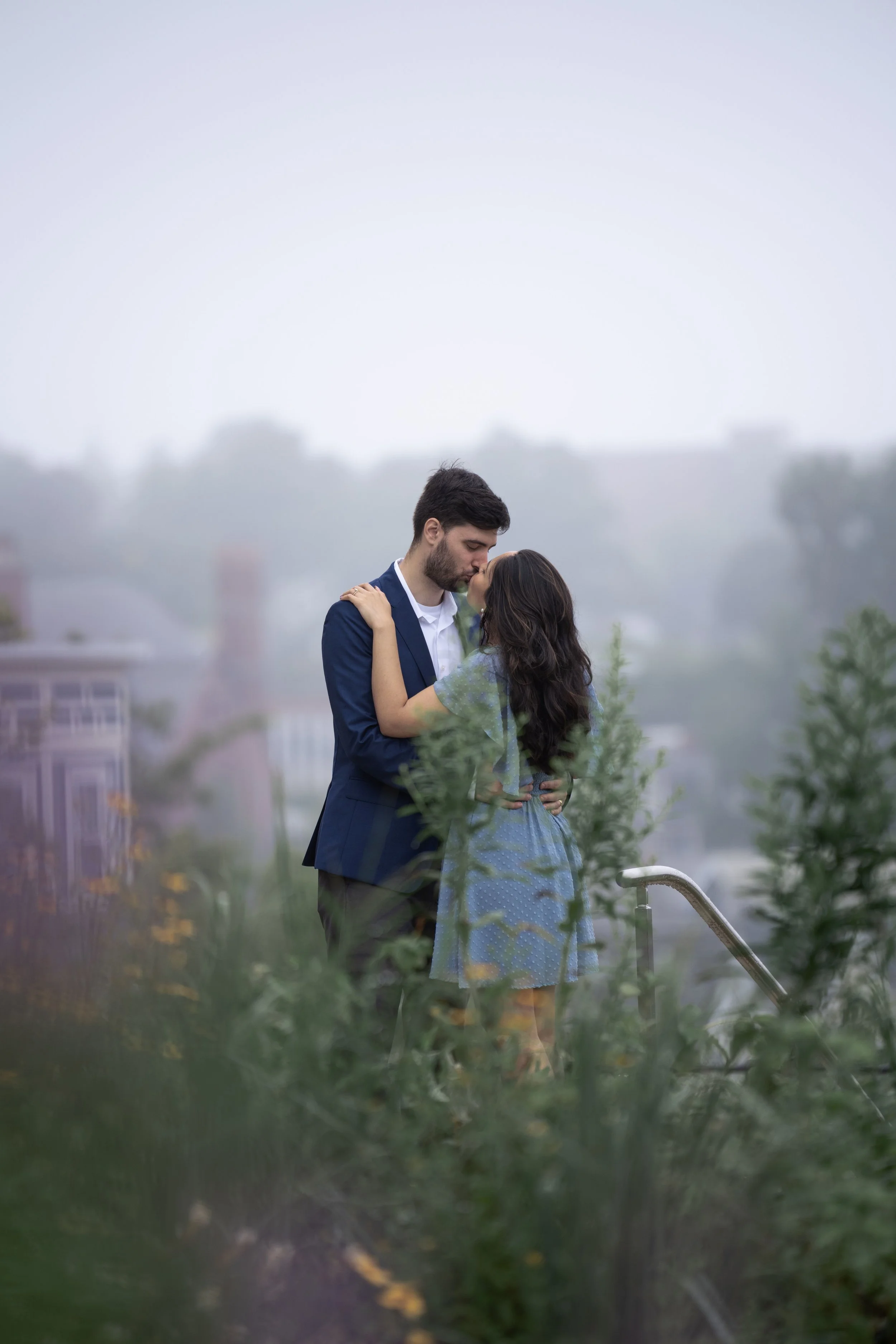 Chris and Nadya exchange a soft kiss amongst wildflowers and the haze of a drizzly rainy day after eloping at the Somerville city hall.