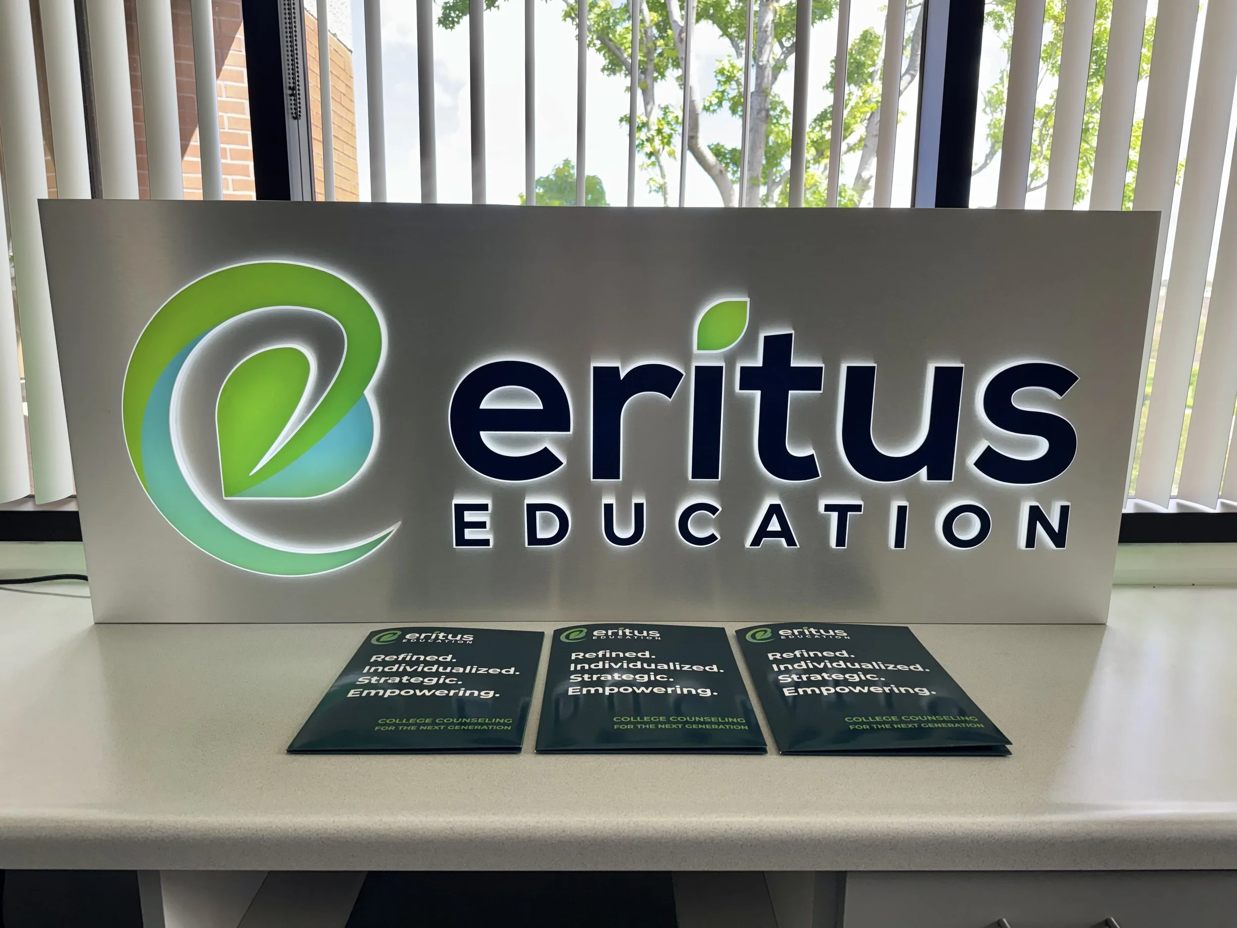Lighted Eritus Education sign in our San Diego college counseling office with informational folders for students and families