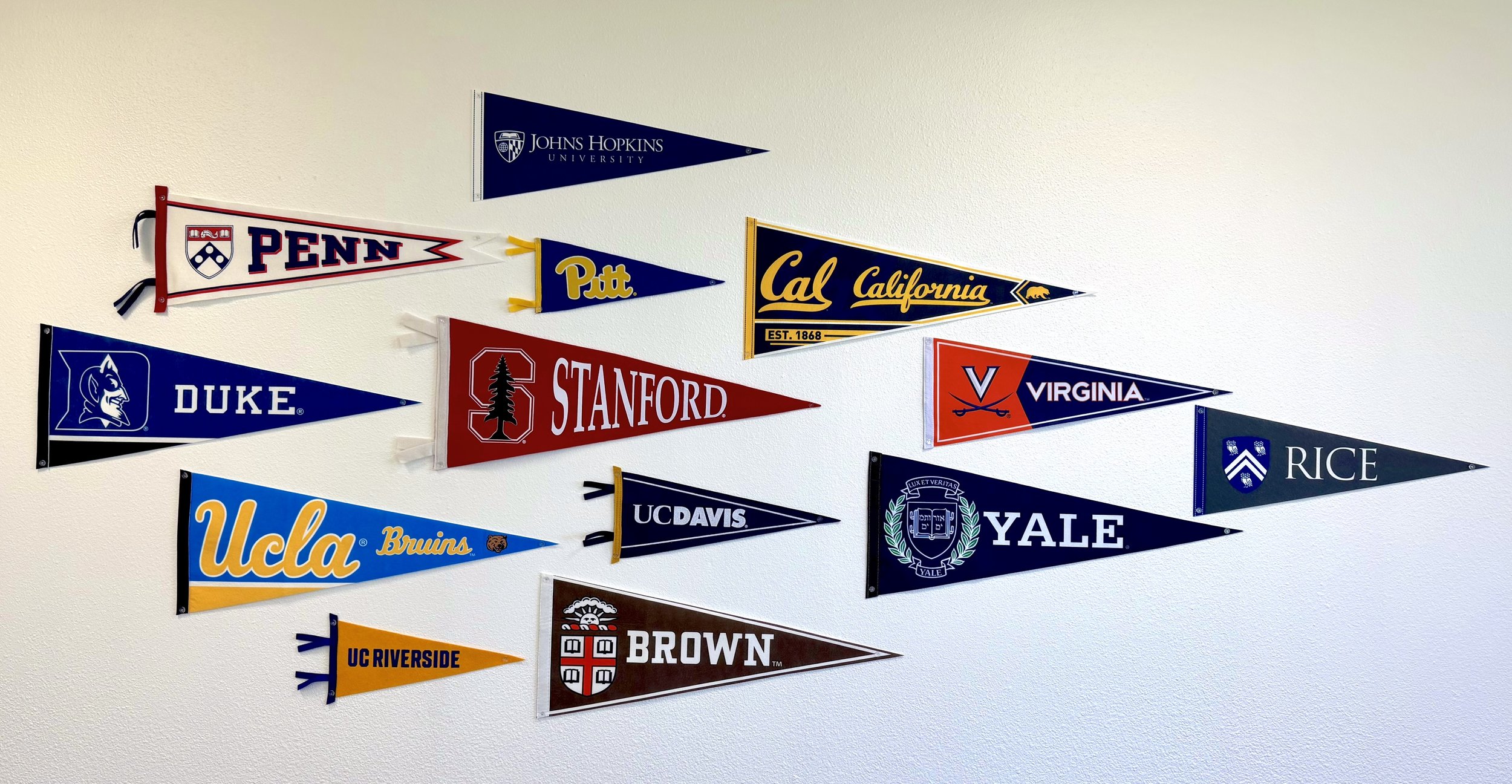 College acceptance pennant flag display in the Eritus Education office featuring universities where our students have earned admission, including Brown, Stanford, UCLA, Yale, and UPenn