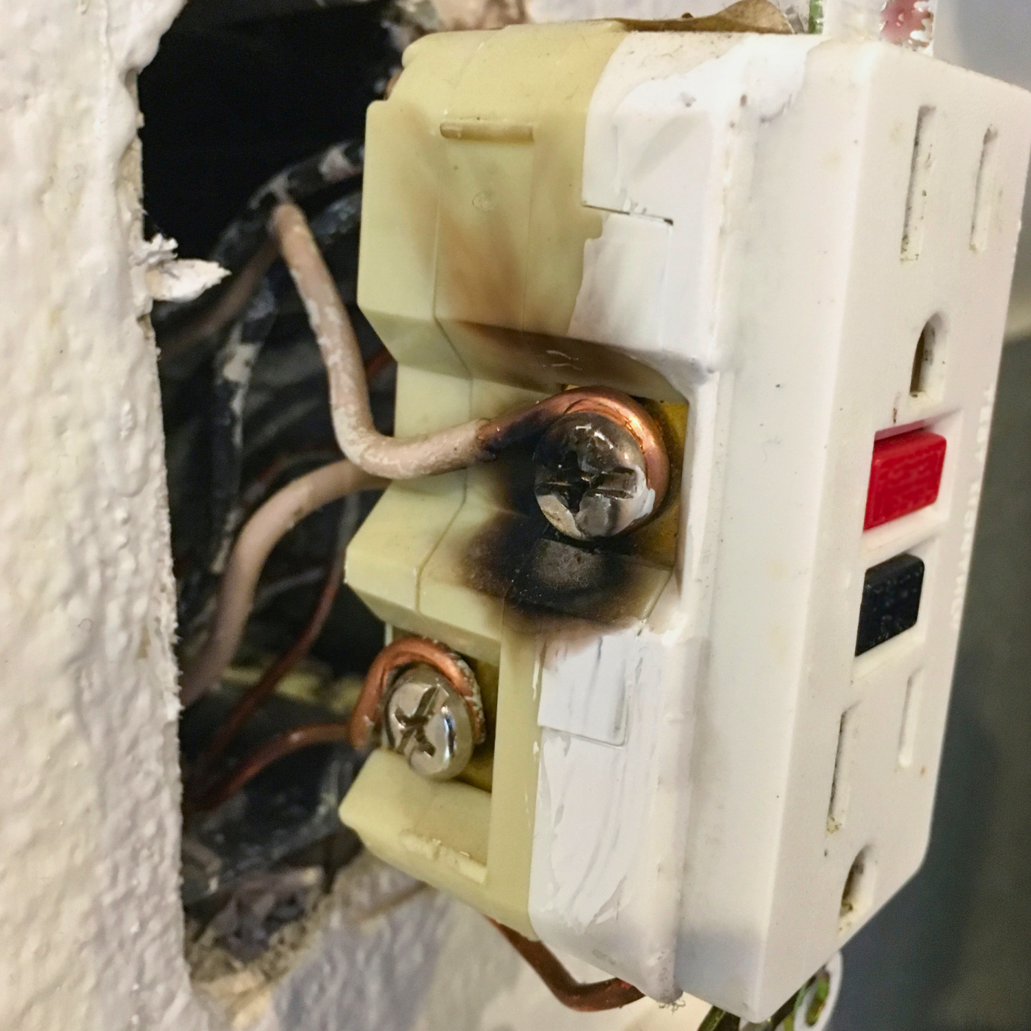 Damaged electrical connections behind outlet — sign of overloaded home wiring