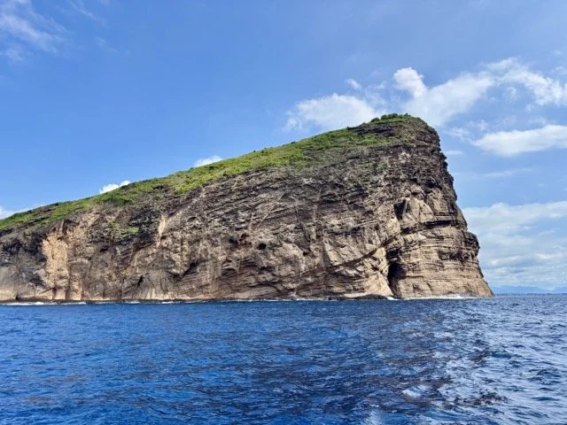 日出時分的出海船隻剪影，背景為 Trou d’Eau Douce 碼頭方向，適合 early morning departure 航拍圖。