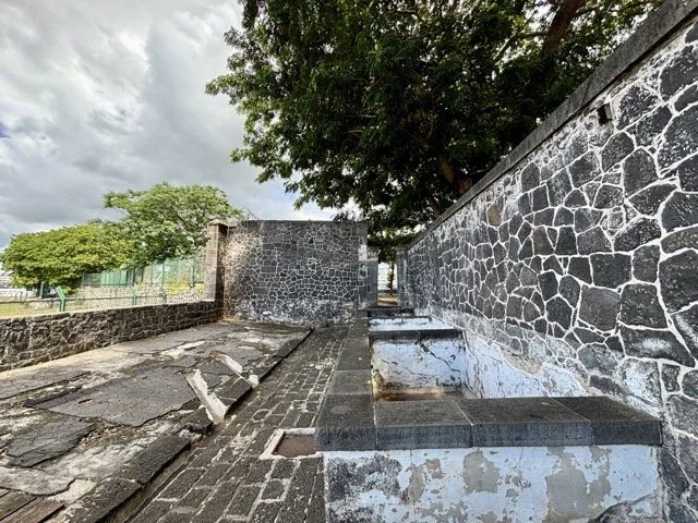 Aapravasi Ghat 遺址全景與導覽牌，說明模里西斯契約勞工歷史，UNESCO 世界文化遺產景觀。 Panorama of Aapravasi Ghat site and interpretive sign explaining indentured labour history, a Mauritius UNESCO World Heritage landmark.