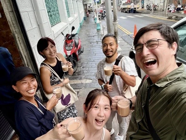 在地導遊 Cindy 帶領旅客穿梭 Port Louis 市場，講述小吃故事與歷史脈絡的互動畫面。 Local guide Cindy leading travelers through Port Louis market telling stories of street food and historical context.