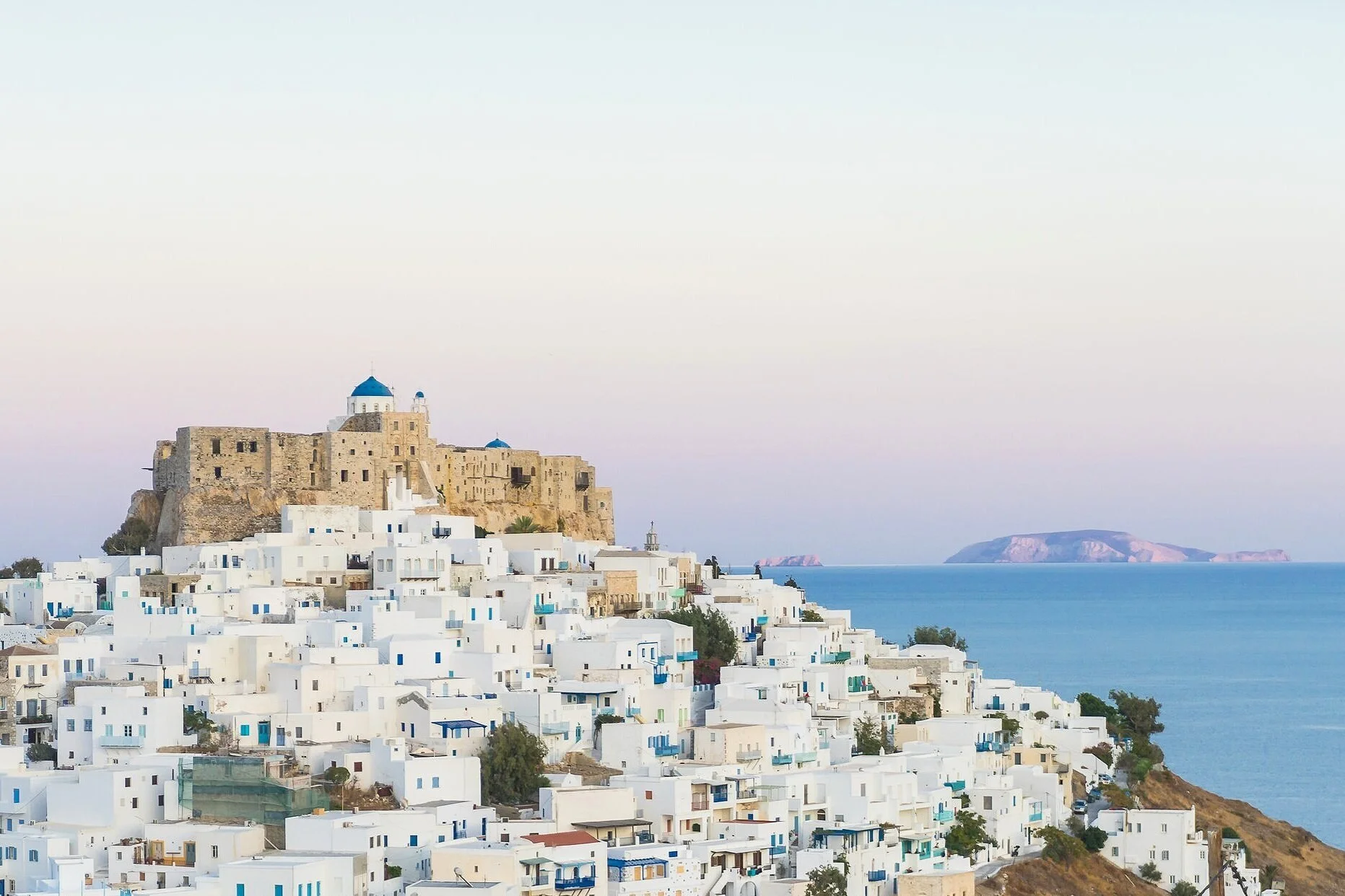 아스티팔리아(Astypalaia) 여행 가이드 이미지: 전통 흰색 주택과 구불구불한 골목, 맑고 잔잔한 에게해 해변이 어우러진 풍경을 담아 아스티팔리아의 매력적인 마을과 해변 포토스팟을 보여줍니다. 골든아워 촬영 포인트, 현지 선착장·페리 접근 정보, 숨은 카페와 마을 산책 루트를 떠올리게 하는 비주얼로 여행자와 사진가에게 유용한 참고 이미지입니다.