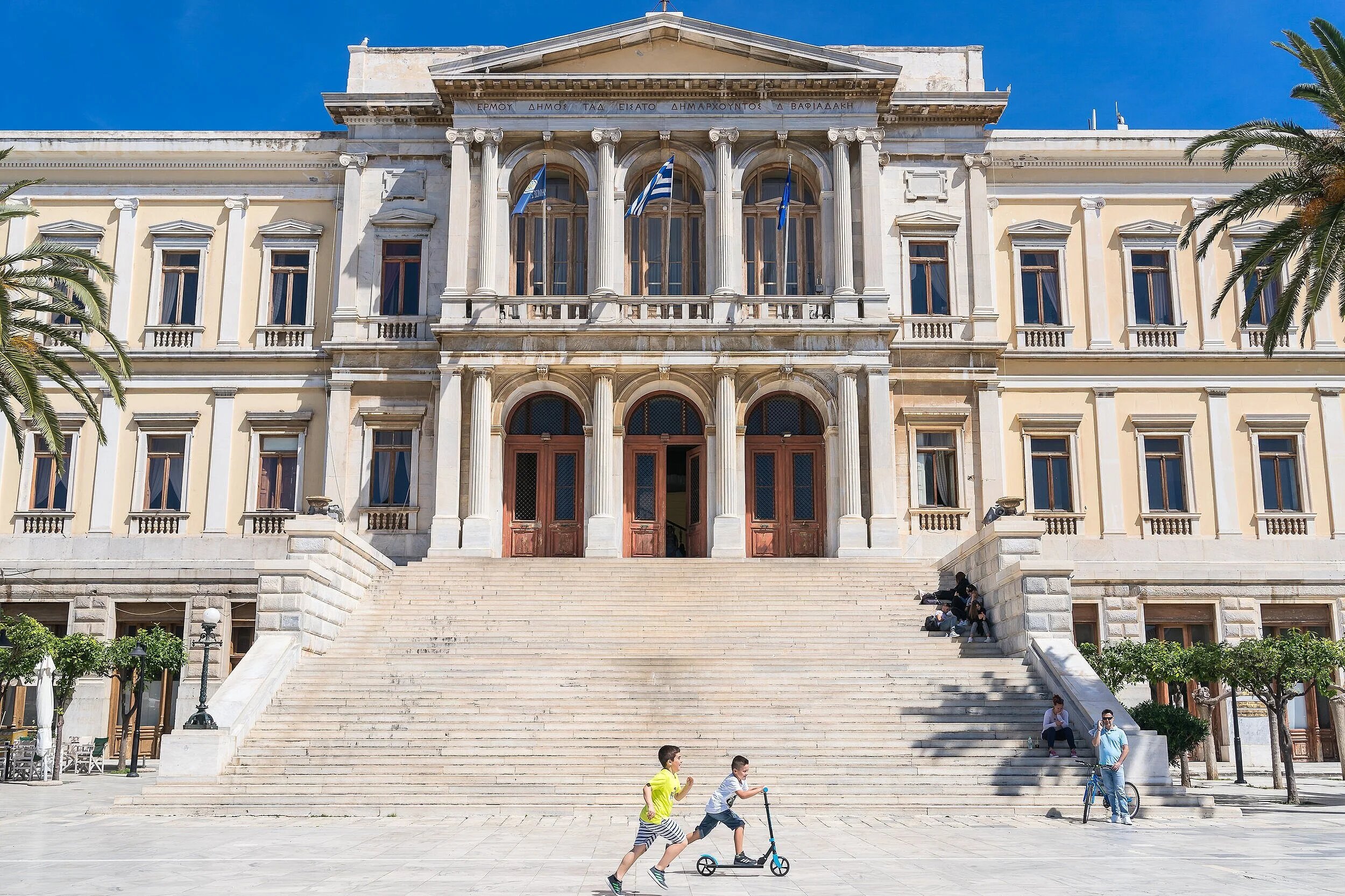 시로스(Syros) 여행 가이드 이미지: 전통적인 네오클래식 건축이 늘어선 시로스 타운과 에메랄드빛 해변, 골든아워에 빛나는 포토스팟을 포착한 풍경으로 관광 명소, 인기 해변(갈락시아 등), 항구 풍경과 여행 사진 촬영 포인트 정보를 연상시키는 비주얼입니다. 시로스의 문화 유적, 카페 거리와 해변 촬영을 계획하는 여행자 및 사진작가에게 최적화된 참고 이미지입니다.