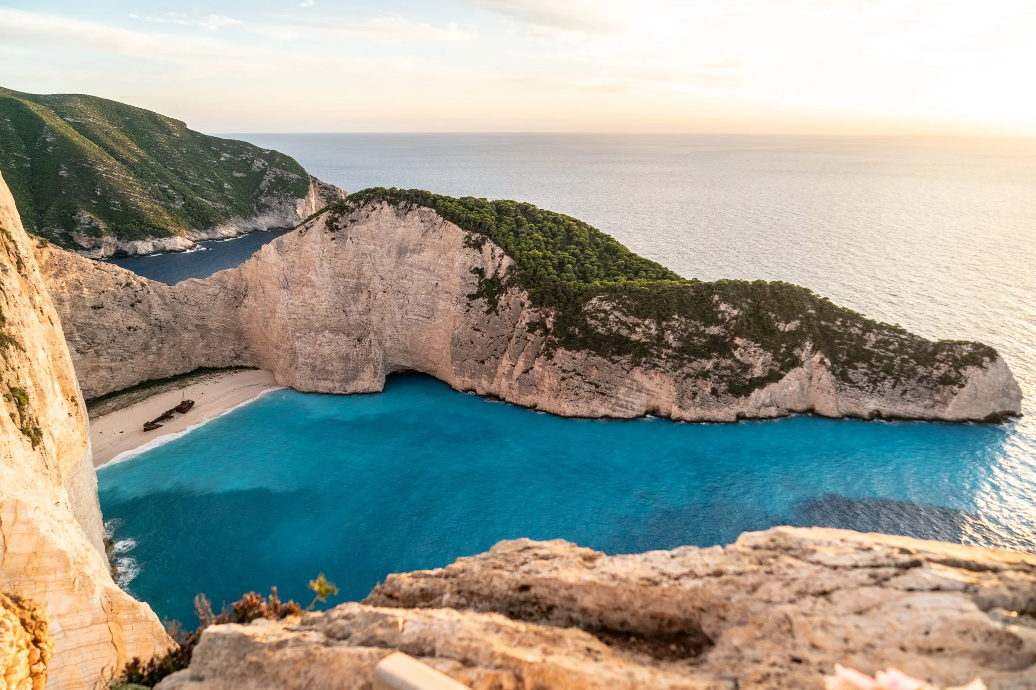 자킨토스(Zakynthos) 여행 가이드 이미지: 에메랄드빛 바다와 상징적 해변(나바지오 해변 등), 전통적인 흰색 마을과 올리브나무가 어우러진 풍경을 골든아워에 포착한 비주얼. 베스트 포토스팟, 보트 투어 정보, 스노클링 포인트 및 인스타그램용 구도를 연상시키며 자킨토스 해변과 마을을 탐방하려는 여행자와 사진가에게 최적화된 참고 이미지입니다.