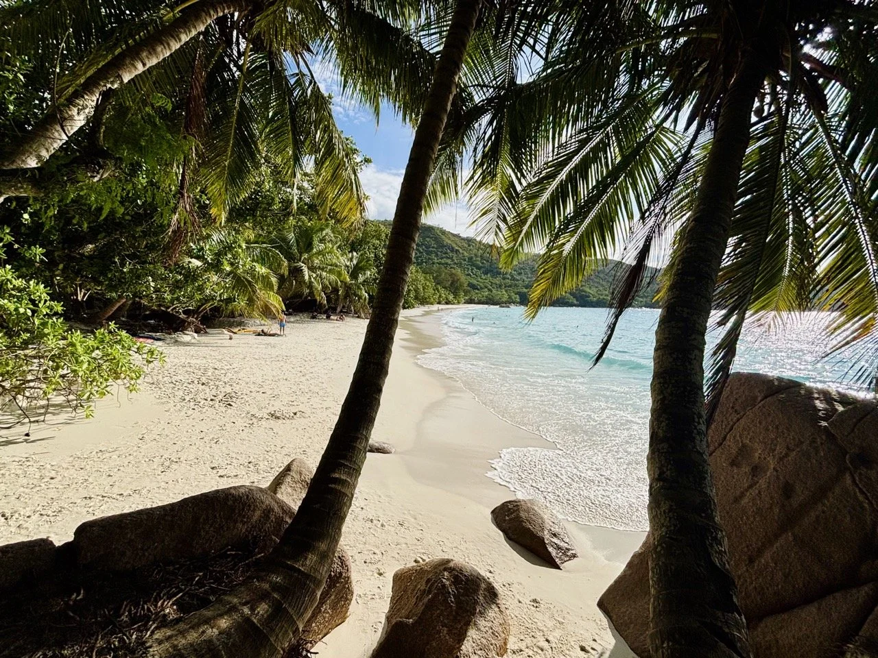 Anse Georgette 清澈的綠松石色海灣，周圍被熱帶植被與山坡環繞，是普拉蘭島自由行的熱門拍攝景點。