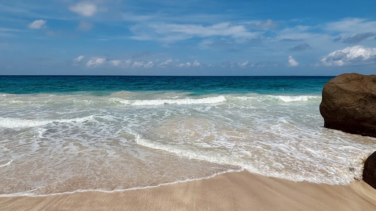 遊客沿著馬埃島 Anse Major 海岸步道健行，背景是清澈海水與崎嶇海岸，適合介紹塞席爾戶外活動。