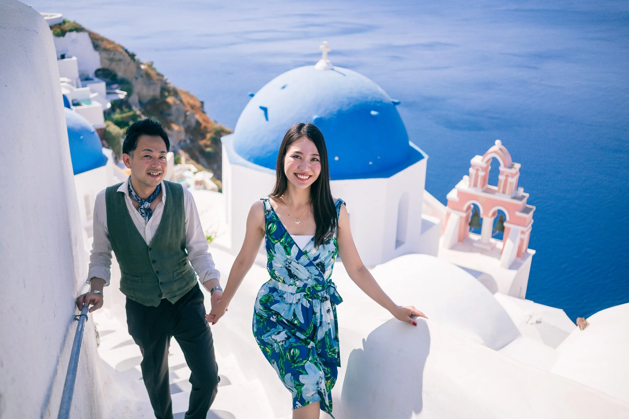 藍頂教堂前的親密人像婚紗：淺景深與自然光強調情感，Oia intimate wedding portrait 建議鏡頭；Intimate portrait at blue domes — shallow depth and natural light emphasizing emotion, recommended lens for Oia portraits.