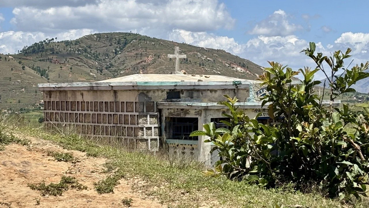 Famadihana 翻屍慶典家族團聚場景：祖先遺骨重新包裹、新布、音樂與舞蹈，展現馬達加斯加的喚祖文化與情感連結；Famadihana family reunion scene — ancestors’ remains rewrapped with fresh cloth, music and dancing, showcasing Madagascar’s ancestor‑veneration ritual and emotional bonds.