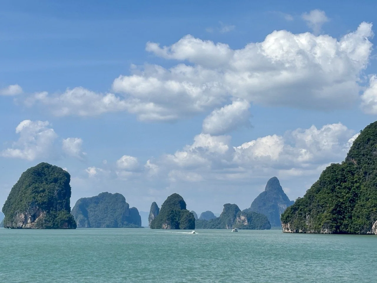從海上眺望 Ko Panyee 班宜島水上人家，背景為攀牙灣石灰岩山壁，是 James Bond Island 行程中的熱門文化景點。