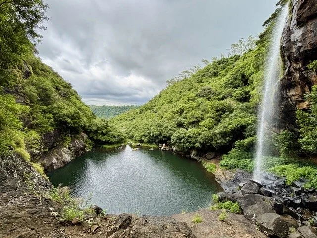 Seven Waterfalls 瀑布群與天然泳池，遊客在林間步道健行並拍攝長曝水景，模里西斯生態景點。Seven Waterfalls cascade and natural pools with hikers on forest trail capturing long exposure waterfall shots, Mauritius eco spot.