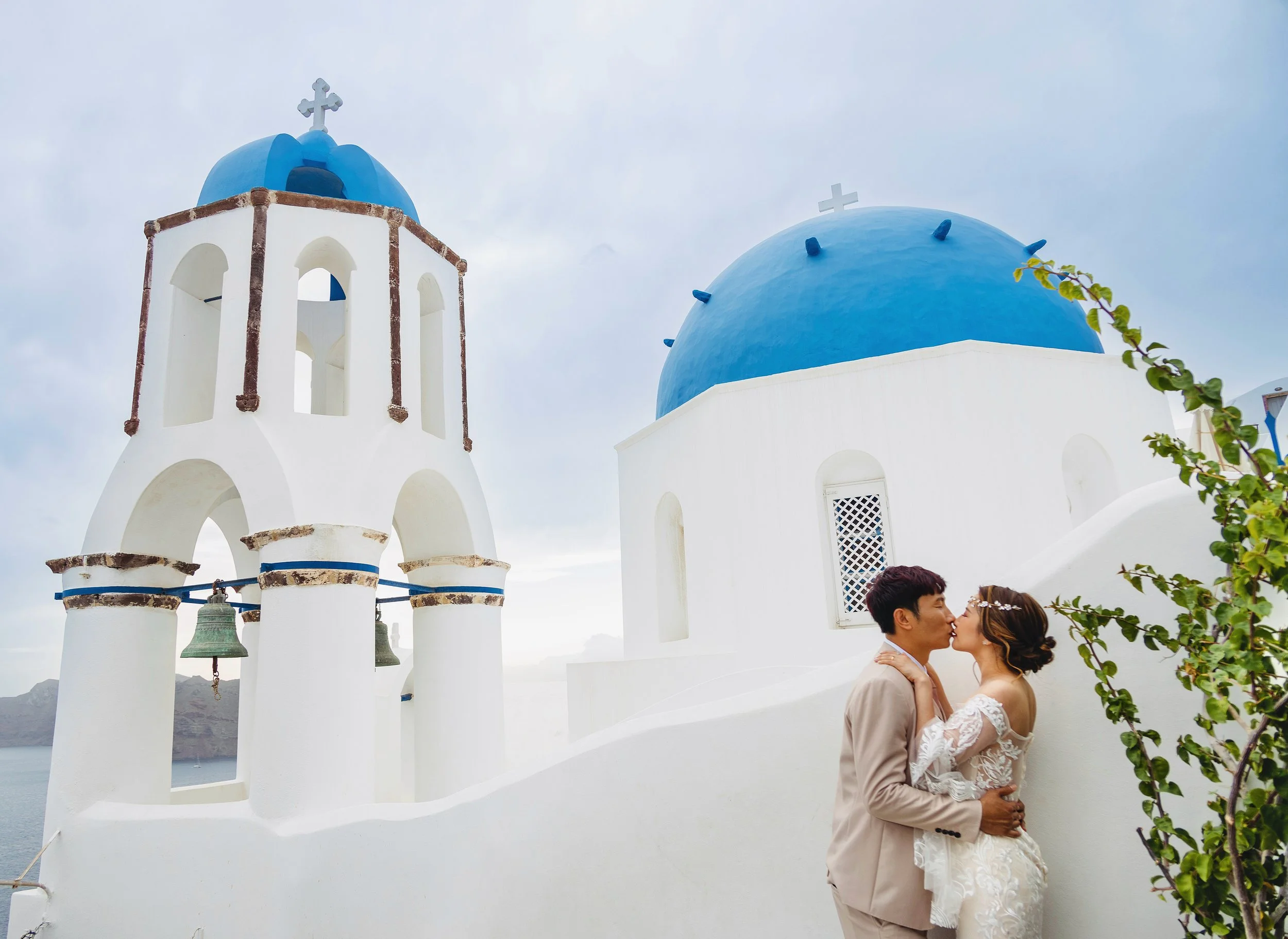 藍頂小徑情侶散步婚紗照：捕捉自然互動與巷弄光影，最佳 Santorini couple walk shot；Couple stroll near blue domes — capture natural interaction and alley light for the best Santorini couple walk shot.