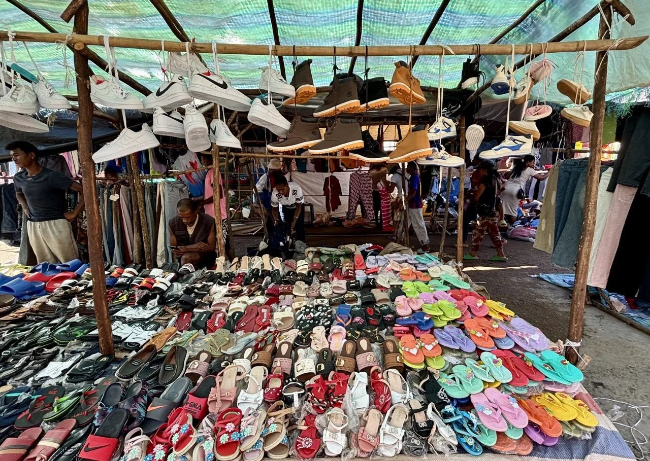 布料與手工織物攤位：彩色紋樣與傳統布料展示，適合紋理與文化細節拍攝；Textiles and fabrics stall at Ranomafana market — colorful patterns and traditional cloths for texture and cultural detail photography.