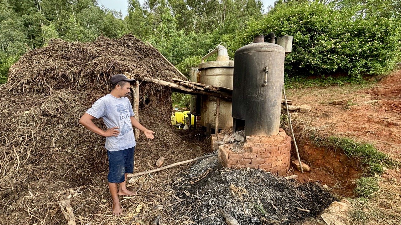 河邊釀酒與蒸餾作坊：傳統蒸餾器與發酵桶，展現馬達加斯加鄉村的家釀技術與社會用途；Riverside distillation workshop — traditional stills and fermentation vats showcasing Madagascar rural homemade spirits techniques and social uses.