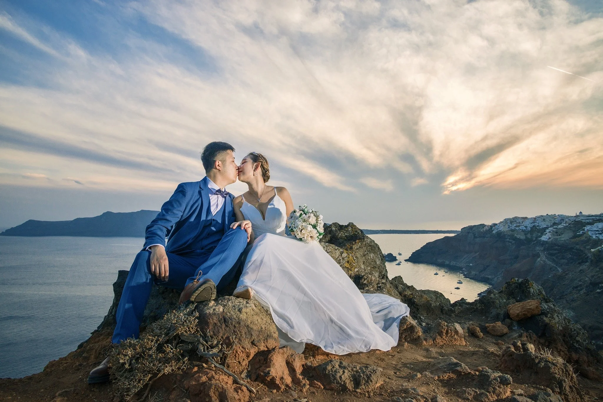 Fira 懸崖線婚紗全景：壯闊 Caldera 與愛琴海背景，黃金時段攝影首選；Fira caldera cliff wedding panorama — dramatic caldera and Aegean backdrop, prime for golden hour shoots.