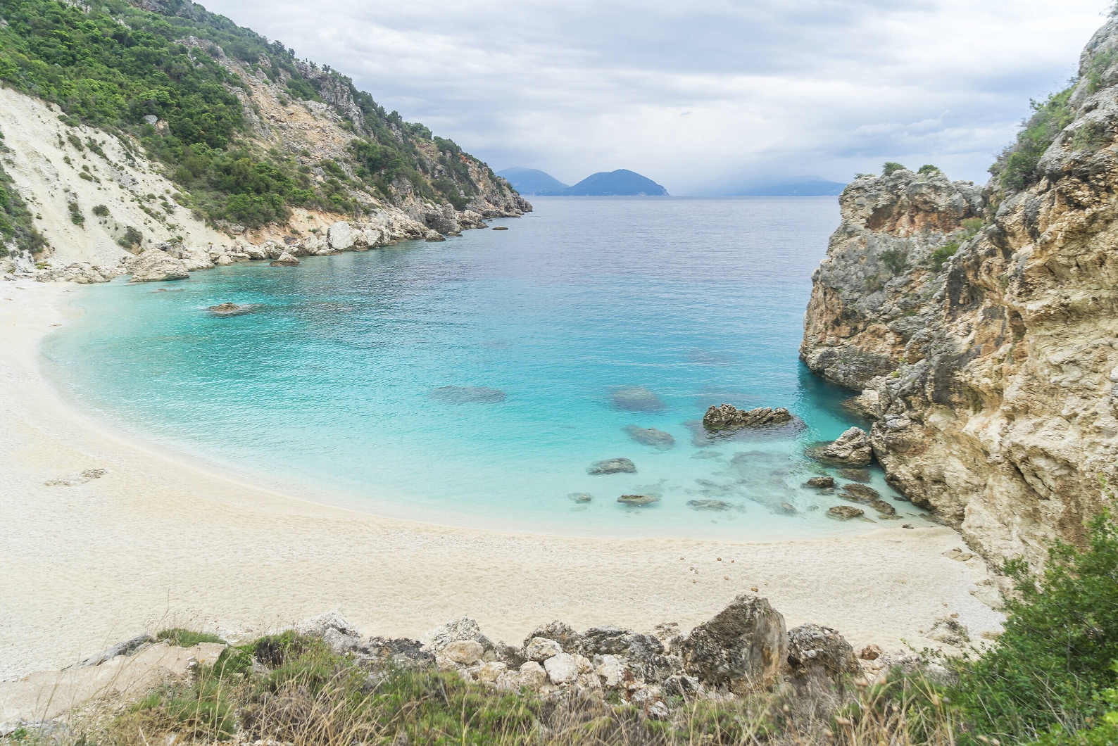レフカダ（Lefkada）トラベルガイド用画像：エメラルドグリーンの海と白砂のビーチが広がるレフカダの絶景を捉え、隠れたフォトスポットやゴールデンアワーの撮影ポイントを想起させるビジュアル。ポルトカテ・エギリ等の人気ビーチ、フェリー／道路でのアクセス、シュノーケリングやボートツアーなどのマリンアクティビティ情報を連想させ、ビーチ巡りや撮影を計画する旅行者向けの参考画像。