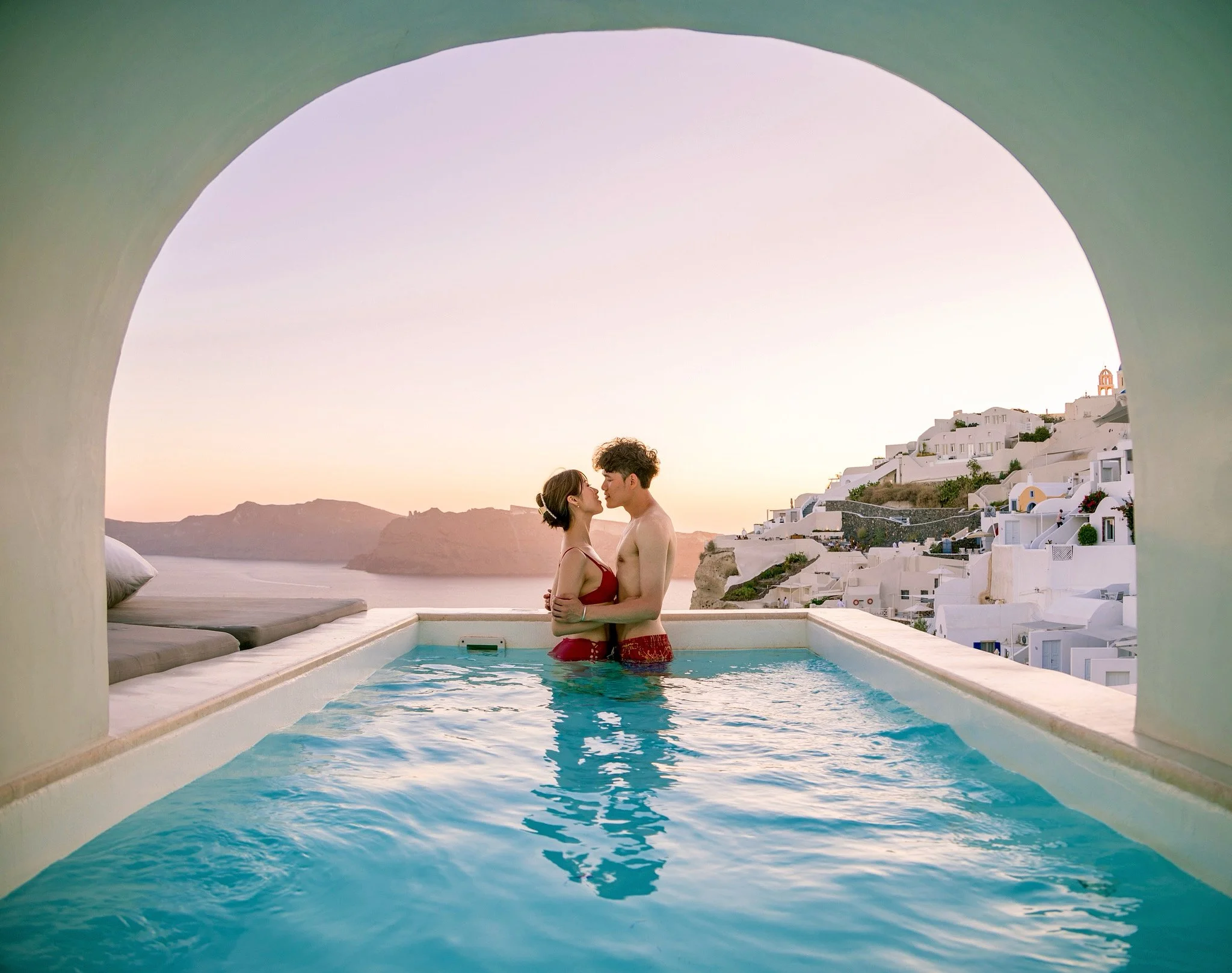 日落倒影情侶照：淺水與濕沙面反射創造對稱浪漫構圖；Sunset reflection couple photo — shallow water and wet sand reflections create symmetrical romantic compositions.