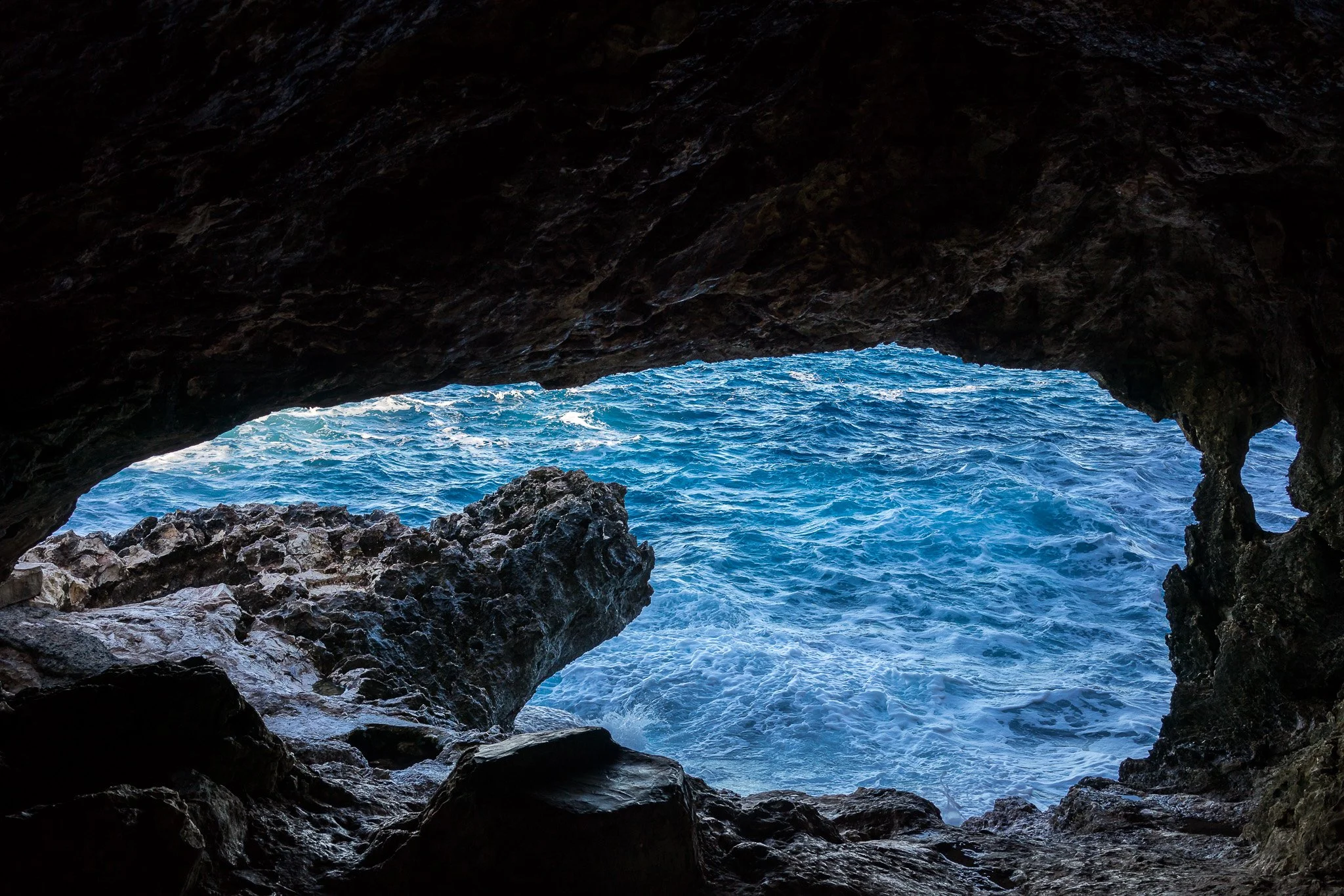 船上視角靠近 Sea Caves 洞口，展示海蝕洞口與碧藍海灣的戲劇性構圖。