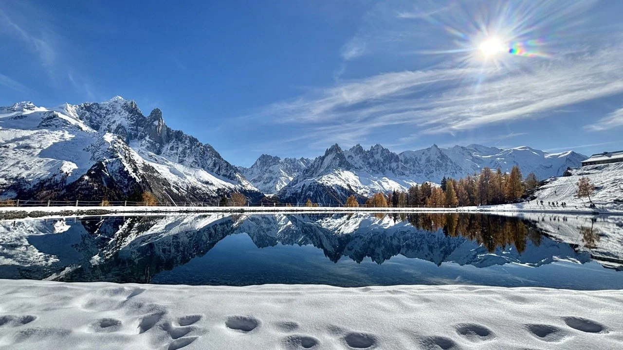 高山湖泊構圖示範：前景岩石、低角度拍攝與鏡面倒影創造視覺深度的技巧；Alpine lake composition example using foreground rocks, low-angle shots and mirror reflections for depth.
